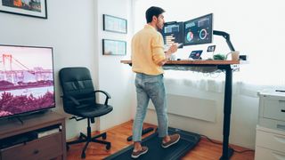 Man walking on an under-desk treadmill at home