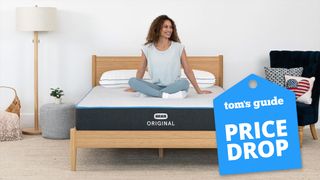 Bear Original Mattress image shows a woman with curly dark hair smiling and sitting cross-legged on the mattress, while a blue price drop sales badge overlaid on the image